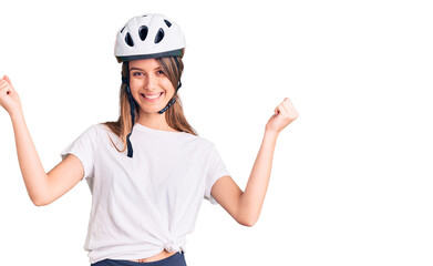 Young beautiful girl wearing bike helmet screaming proud, celebrating victory and success very excited with raised arms