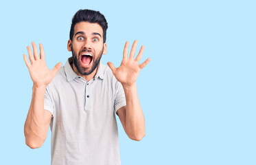 Fototapeta premium Young handsome man with beard wearing casual polo celebrating crazy and amazed for success with arms raised and open eyes screaming excited. winner concept
