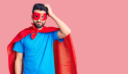 Young handsome man with beard wearing super hero costume confuse and wonder about question....