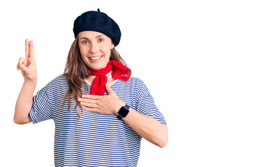 Young beautiful blonde woman wearing french beret and striped t-shirt smiling swearing with hand on...
