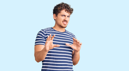 Young handsome man with curly hair wearing casual clothes disgusted expression, displeased and...