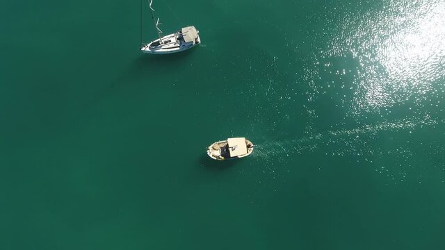 Flying above a small traditional boat that is passing by a sailing yacht