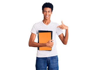 Young african american man holding book smiling happy pointing with hand and finger