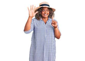 Obraz na płótnie Canvas Young african american plus size woman wearing summer hat showing and pointing up with fingers number six while smiling confident and happy.