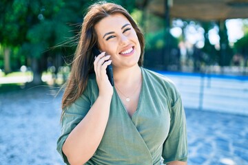 Young hispanic woman smiling happy talking on the smartphone walking at street of city