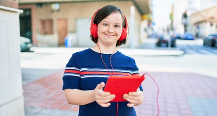Beautiful brunette woman with down syndrome at the town on a sunny day using touchpad device...