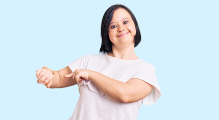 Brunette woman with down syndrome wearing casual white tshirt in hurry pointing to watch time,...