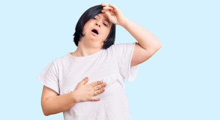 Brunette woman with down syndrome wearing casual white tshirt touching forehead for illness and...