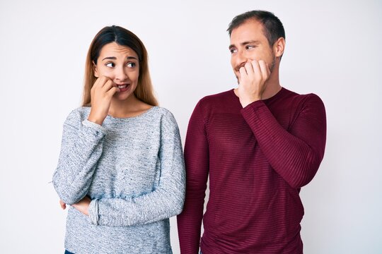 Beautiful couple wearing casual clothes looking stressed and nervous with hands on mouth biting nails. anxiety problem.