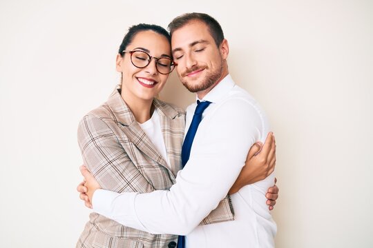 Beautiful couple wearing business clothes hugging oneself happy and positive, smiling confident. self love and self care