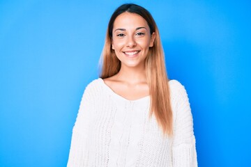Young brunette woman wearing casual sweater looking positive and happy standing and smiling with a confident smile showing teeth