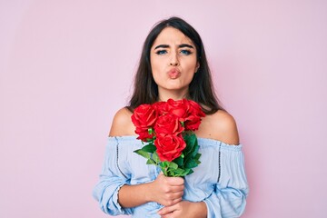 Brunette teenager girl holding flowers looking at the camera blowing a kiss being lovely and sexy. love expression.