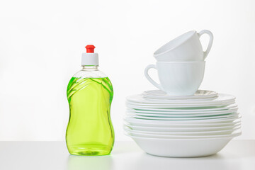 Green dish washing gel and a set of plates on a light background.