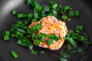 Frozen carrots and green onions in a black pan. Roasters
