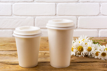 Paper coffee cups mockup with daisy wildflowers