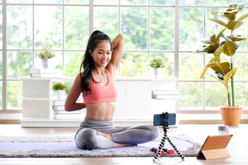 Fototapeta na wymiar Exercise online training class at home, Asian girl sttretch body while workout, Healthy asia woman training exercise by mobile phone, Female sport blogger recording video by smartphone