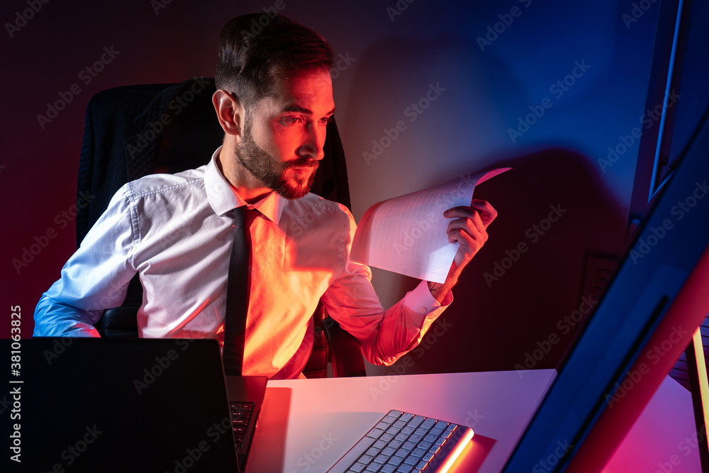 Poster a man is working at a computer on a dark background with red lighting. performing urgent work. a bea