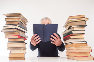 Reading of books. The man is surrounded by stacks of books. Home library. Reading as a hobby. Passion for books.