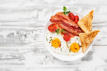 American breakfast with two fried eggs,tomato salad,bacon and toast. top view