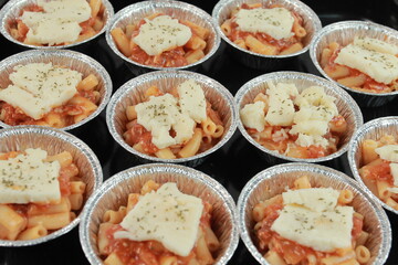 baked macaroni with bolognese sauce, cheese and meat. In round aluminum foil packaging, 8 cm in...