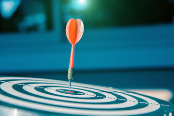 Bulls eye or dart board has red dart arrow throw hitting the center of a shooting target for...