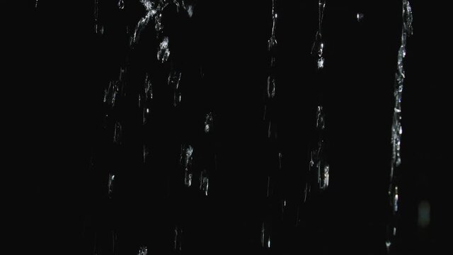 Jets of rain flow down the canopy in slow motion. Water streams close up isolated on black background.