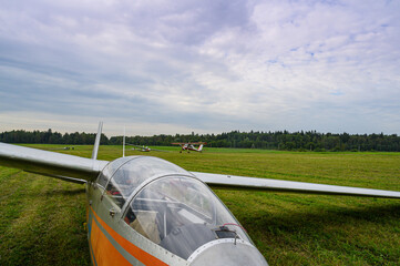 a glider is landed on a green grass of  an airdrome field in russian countryside