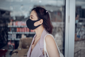 Asian female with medical mask on the city street. Life during covid-19 pandemic.