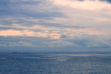 夜明けの大阪湾、神戸新港突堤から雲に覆われた空から朝日が覗く。