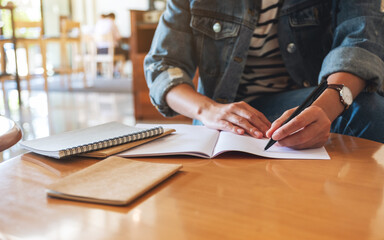 Closeup image of a woman writing on a notebook on the table
