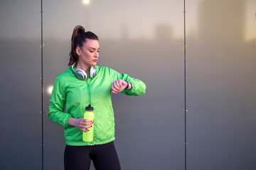 Fit young woman with bottle of water in her hands resting after exercise