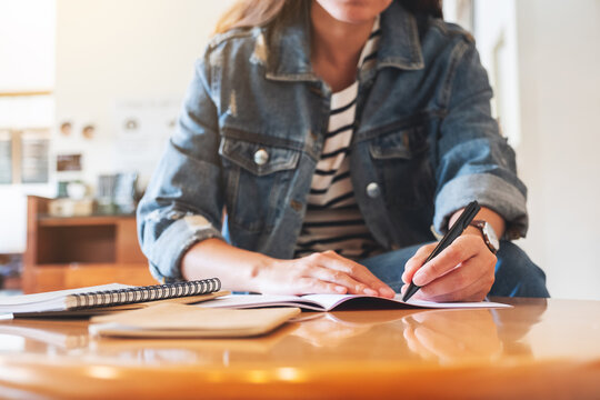 Closeup image of a woman writing on a notebook on the table