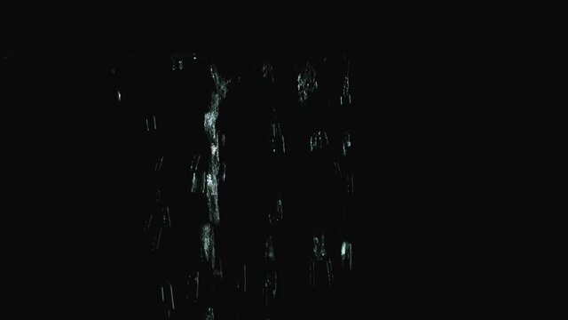 Jets of rain flow down the canopy in slow motion. Water streams close up isolated on black background. Bottom view of raindrops, splashes and flowing streams of water.