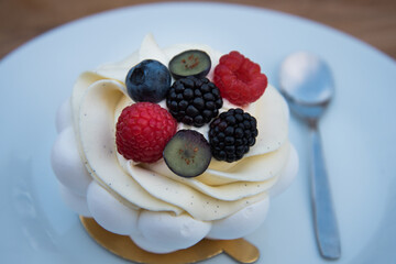 Close-up of a pie with whipped cream and berries. Pie on a white plate.