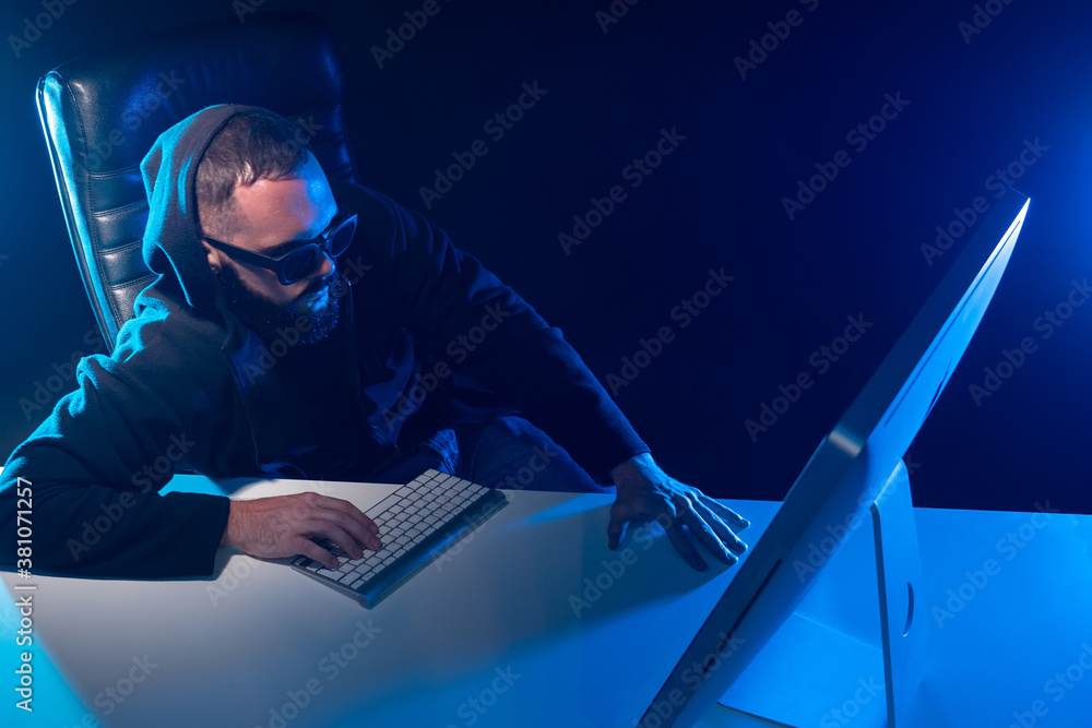 Poster hacker next to computer. man is typing something. guy in the hood looks at the monitor. concept - ha