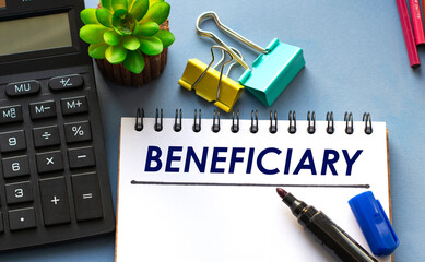 BENEFICIARY word is written in a notebook with a marker, calculator, clamps and cactus