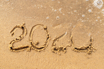 2020 text painted on the sand. Water washed away the text on the beach. The 2021 year is coming.