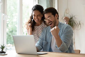 Overjoyed millennial man and woman triumph win online lottery on laptop. Happy excited young...