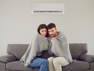 Freezing couple in cool room cuddling in plaid