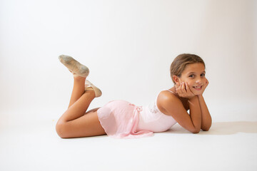 Beautiful little ballerina lying on the floor on white background © Danko