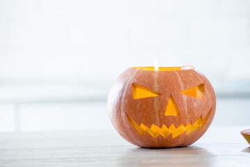 Orange halloween pumpkin with carved face in white kitchen, holiday decoration