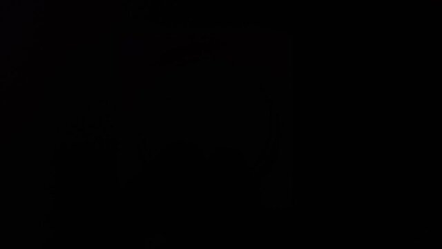 A man's hand turns off the light switch and it becomes dark. Close up.