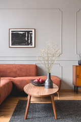 Retro wooden cabinet with black vases in the corner of classy grey living room interior with ginger...