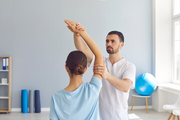 Young male osteopath masseur in white clothes kneads the joints of the girl's hand.