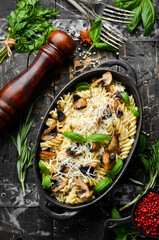 Pasta with mushrooms, parmesan cheese and basil in a black pan. Top view.