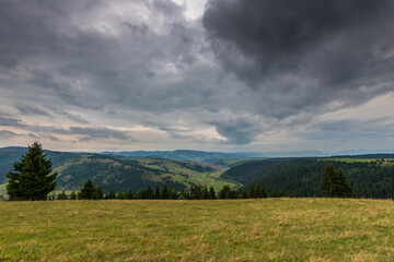 Landscape view from the top of the mountain in the Carpathian mountains, Romania, dramatic storm clouds in the background.