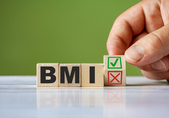 hand turn wooden block with red reject X and green confirm tick as change concept of BMI. Word BMI conceptual symbol.