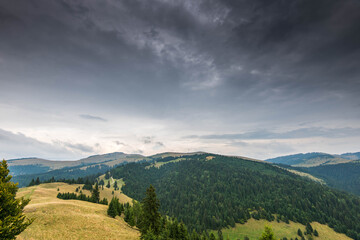 Landscape view from the top of the mountain in the Carpathian mountains, Romania, dramatic storm clouds in the background.