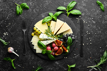 Assorted cheeses on a plate. Parmesan cheese, blue cheese and brie on a plate with grapes and figs. Antipasto. Top view.