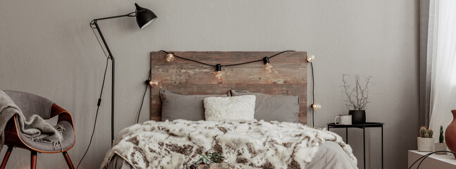 Panoramic photo of rustic bedroom interior with cozy bed with warm blanket